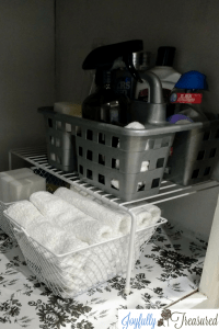 Under the sink organization ideas. Use a simple wire shelf, a dollar tree caddy, and baskets to organize the under the sink essentials. Floral contact paper as an adhesive covering for the cabinet floor.