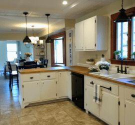 Farmhouse kitchen remodel on a budget with painted white cabinets, butcher block countertops, recessed and pendant lighting and oil rubbed bronze bridge faucet. Lots of budget remodeling ideas and inspiration. #kitchenremodel #farmhouse