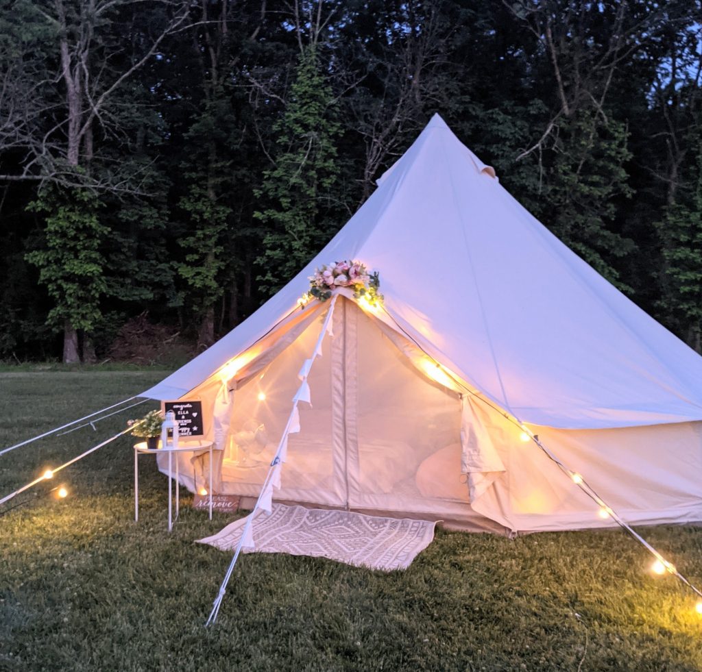 bell tent lit up at night for a backyard glamping party, diy glamping slumber party