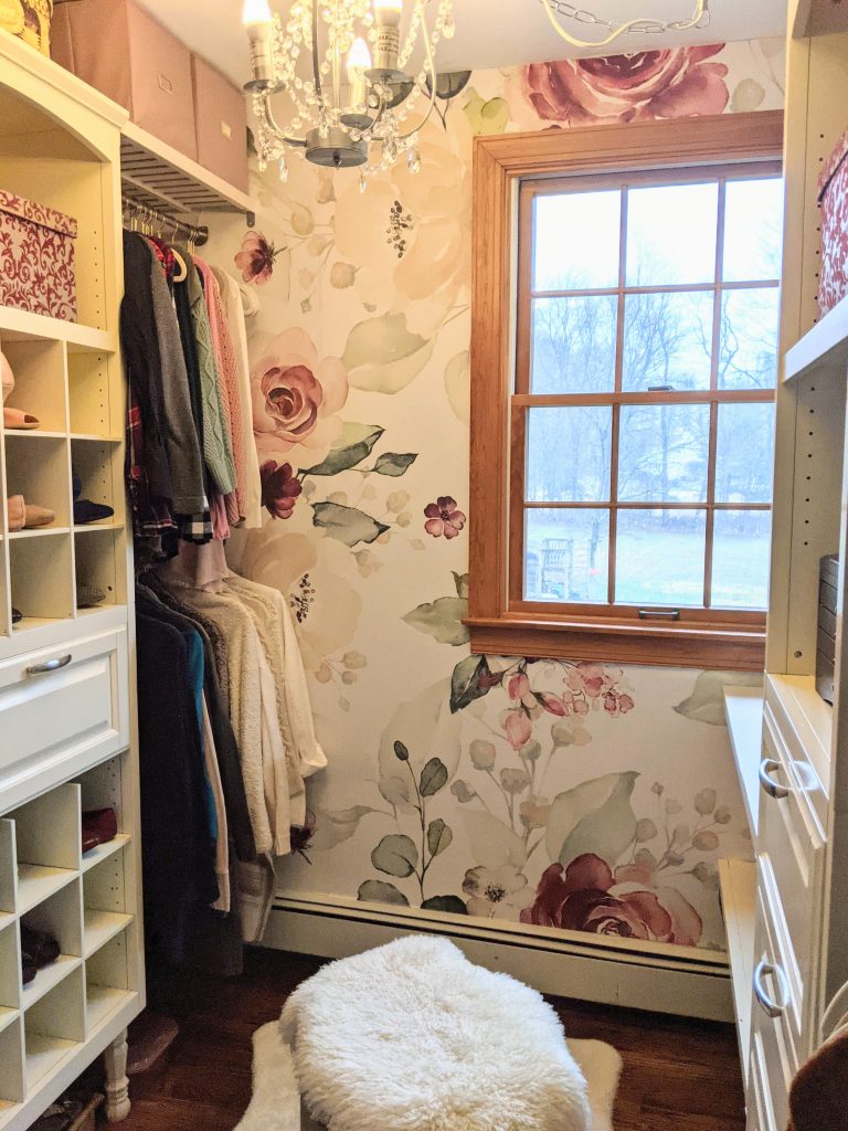 Walk-in closet with Allen Roth wood closet system from lowes in antique white, fully styled with hanging clothes, drawers, and shoe cubbies.