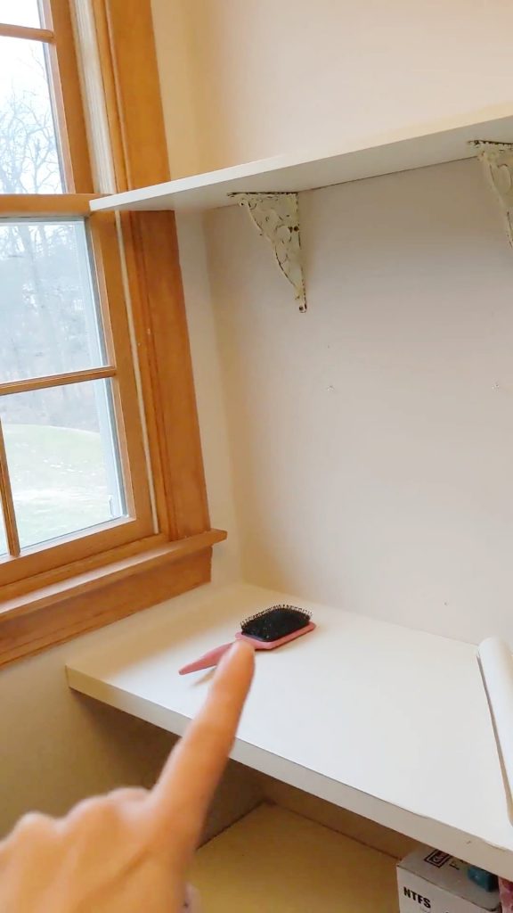 Unstyled built-in vanity area between wood closet kits before adding decor, featuring natural light from window